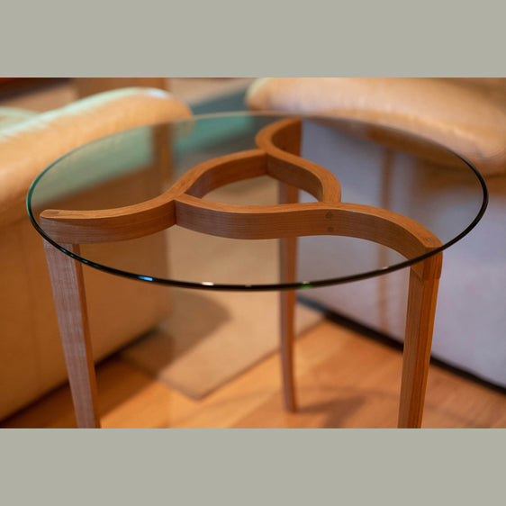 Round glass topped wood end table with modern design