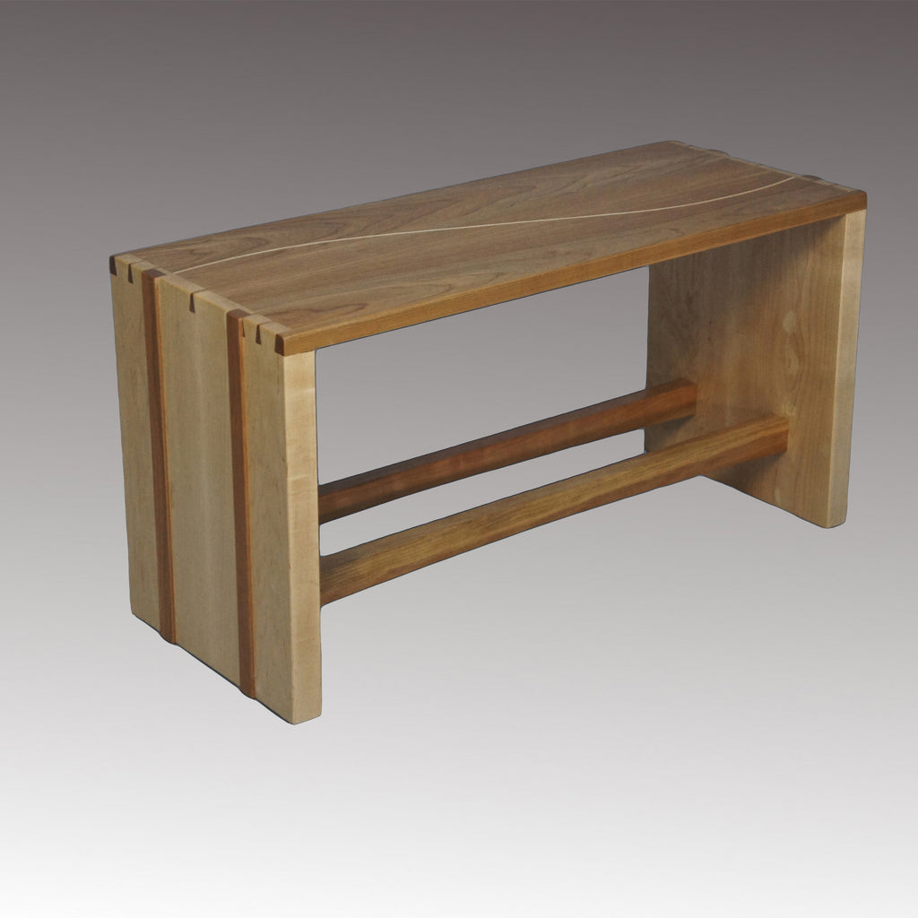 A solid wood bench of cherry and maple with dovetailed  joinery